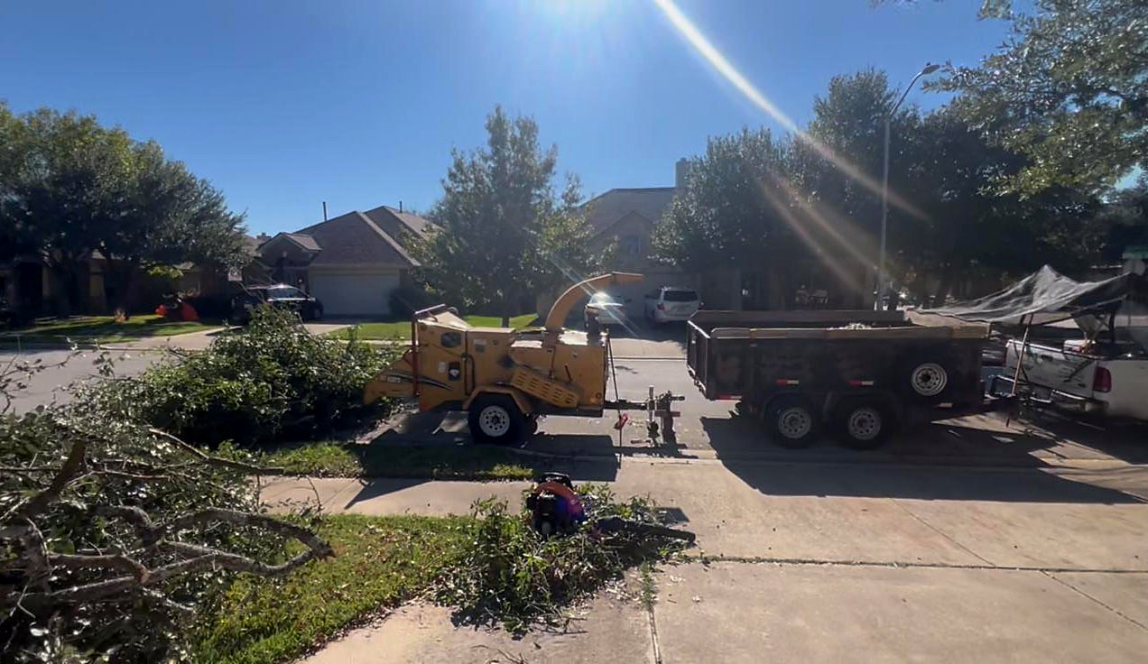 Wood chipper and dump trailer cleaning up branches on a residential street